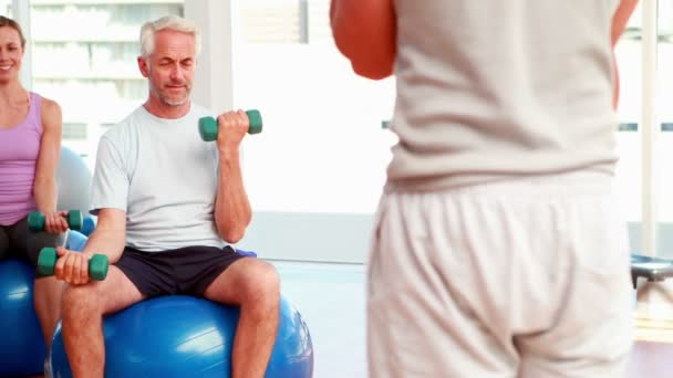 Übungsstunde auf Gymnastikbällen beim Heben von Handgewichten — Stockvideo