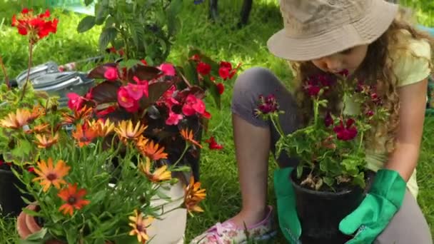 Linda chica sosteniendo una olla de flores en el jardín — Vídeos de Stock