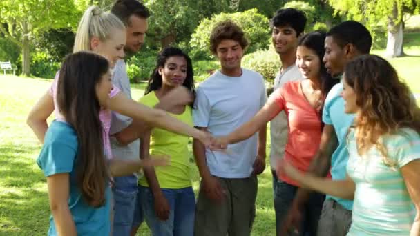 Groep casual jonge vrienden hun handen samenstellen — Stockvideo