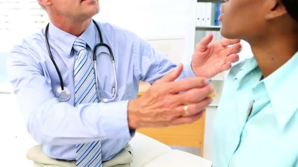 Врач проверяет горловые железы своего пациента — стоковое видео
