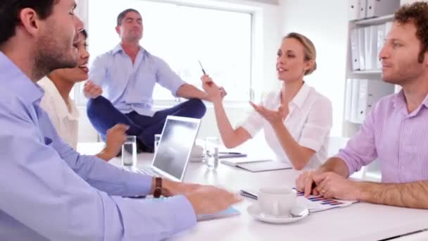 Hombre de negocios guapo meditando mientras sus colegas están discutiendo — Vídeos de Stock