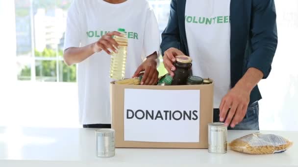 Young volunteer team packing a food donation box — Stock Video