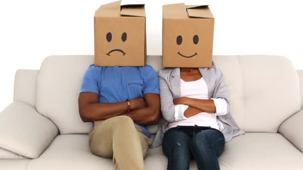 Partners sitting on sofa with emoticon boxes on their heads — Stock Video