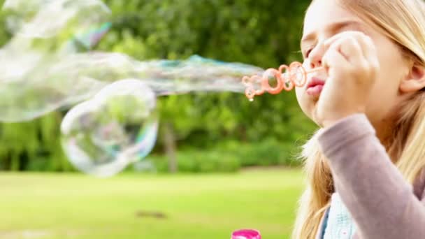 Söt liten flicka som blåser bubblor i park — Stockvideo