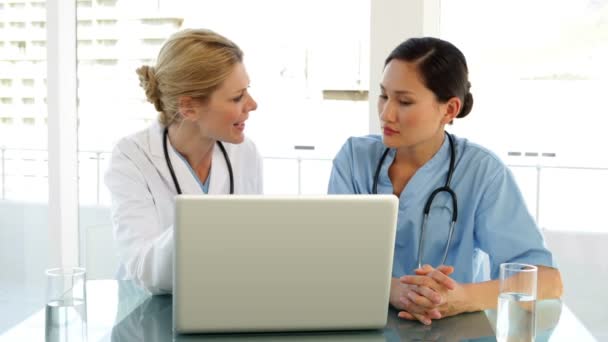 Médico y enfermera revisando un archivo en el portátil — Vídeo de stock