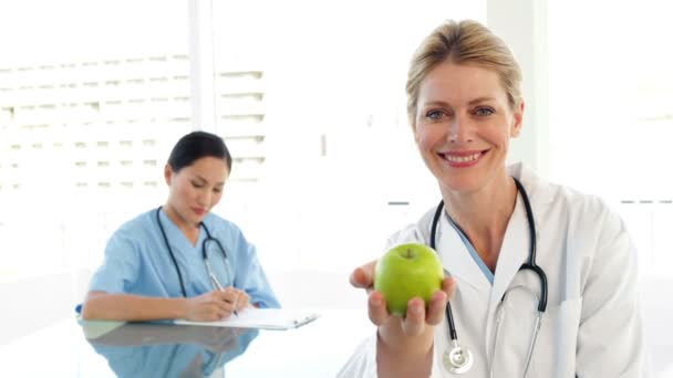 Médico sonriente mostrando una manzana verde — Vídeos de Stock