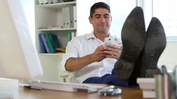Бизнесмен берёт трубку с поднятыми ногами на столе — стоковое видео