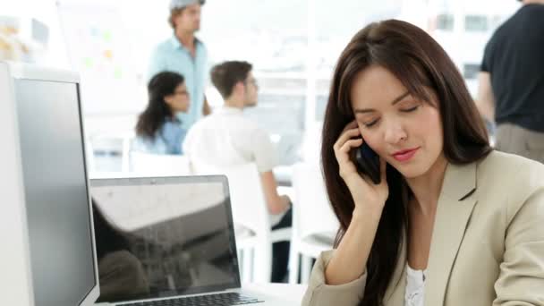 Žena pracující u svého stolu mluví po telefonu — Stock video