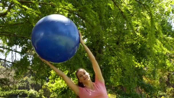 Mujer en forma levantando la pelota de ejercicio en el parque — Vídeo de stock