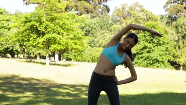Underbara passar brunett stretching i parken — Stockvideo