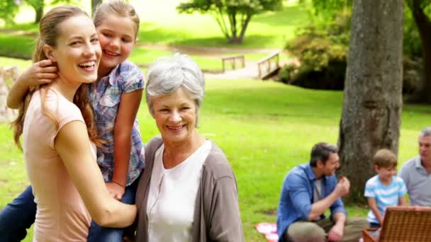 Three generations of women smiling at camera with men behind — Stock Video