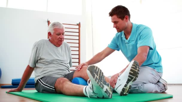 Fysiotherapeut patiënt helpen met zijn knie mobiliteit — Stockvideo