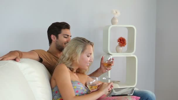 Pareja acostada en el sofá usando la tableta pc beber vino — Vídeos de Stock