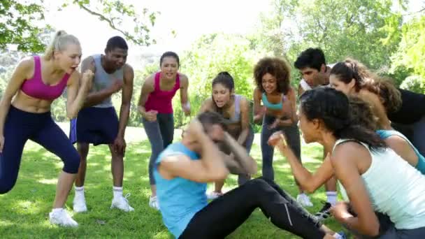 Fitness group cheering on man doing sit ups — Stock Video