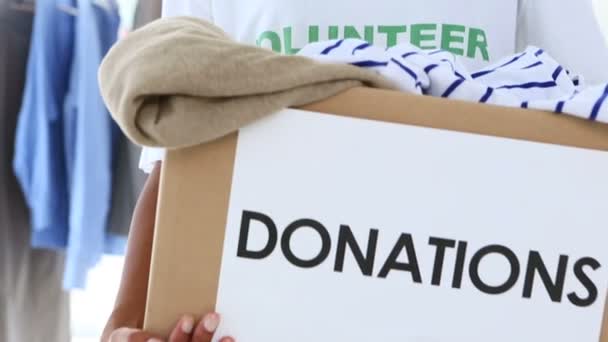 Bonito voluntário segurando uma caixa de doação de roupas — Vídeo de Stock