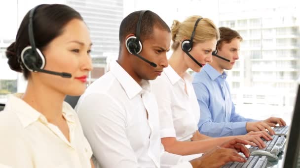 Call centre agents working with one smiling at camera — Stock Video