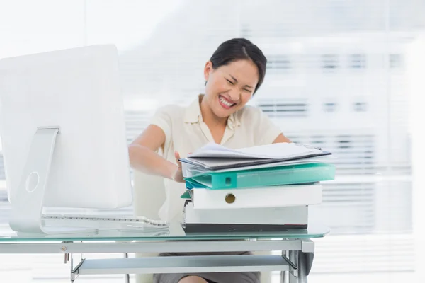 Angry businesswoman with stack of folders at desk — Stock Photo, Image