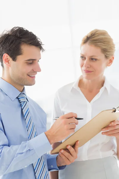 Smiling business team working from clipboard together Stock Image