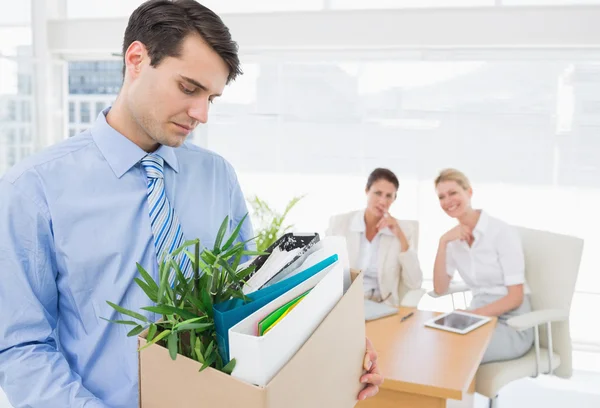 Businessman carrying his belongings with colleagues in backgroun — Stock Photo, Image