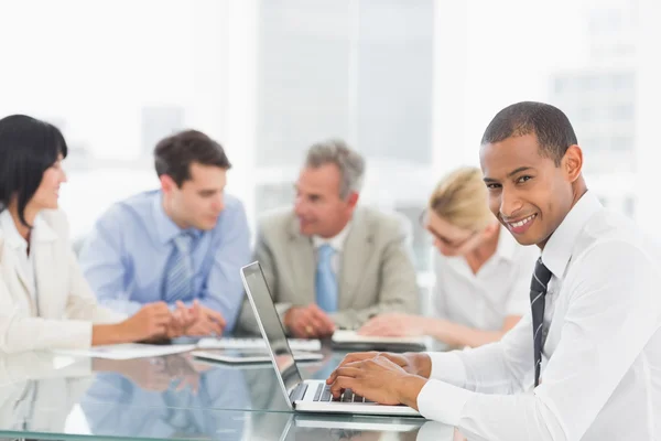 Empresario usando laptop durante una reunión sonriendo a la cámara —  Fotos de Stock