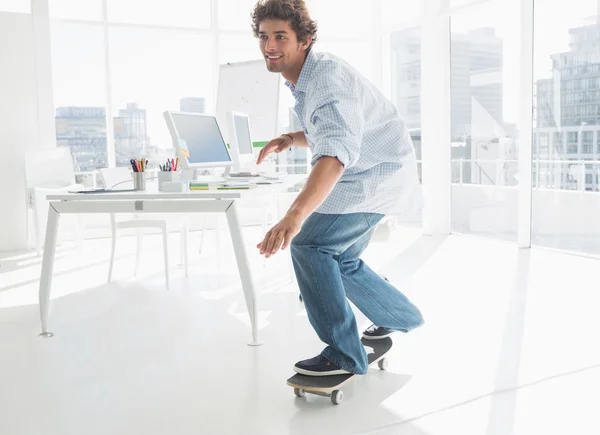 Szczęśliwy młody człowiek skateboarding w biurze — Zdjęcie stockowe