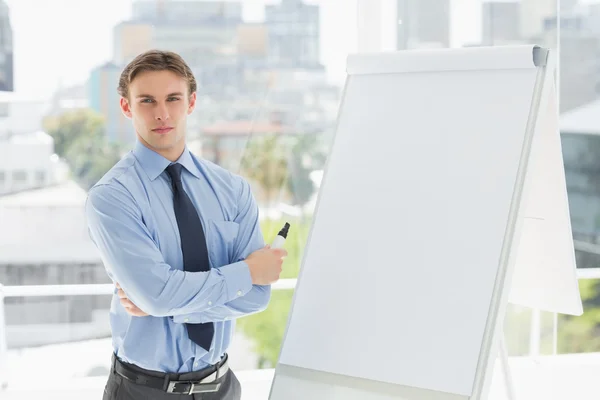 Young stern businessman standing by whiteboard — Stock Photo, Image