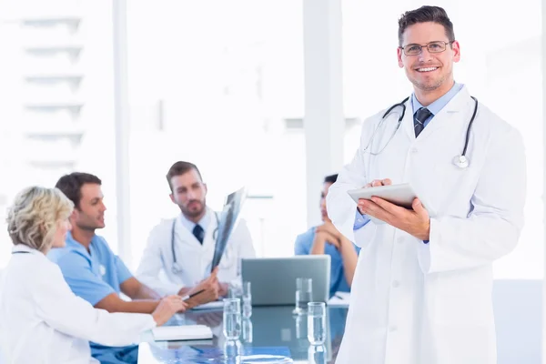 Γιατρός χρησιμοποιώντας ψηφιακή δισκίο με τους συναδέλφους συνεδρίαση — Φωτογραφία Αρχείου