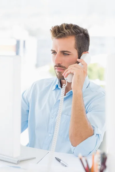 Homem sério usando telefone e computador no escritório — Fotografia de Stock