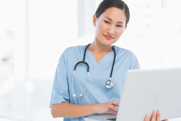 Smiling female surgeon using a laptop — Stock Photo, Image