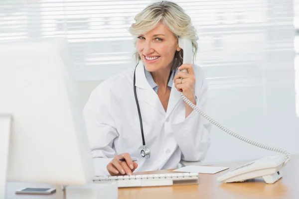 의료 사무실에 전화를 사용 하 여 컴퓨터와 함께 여성 의사 — 스톡 사진