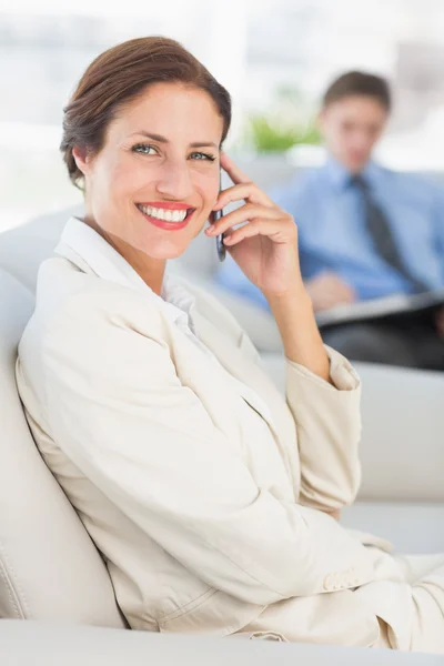 Glada affärskvinna på telefonen sitter på soffan — Stockfoto