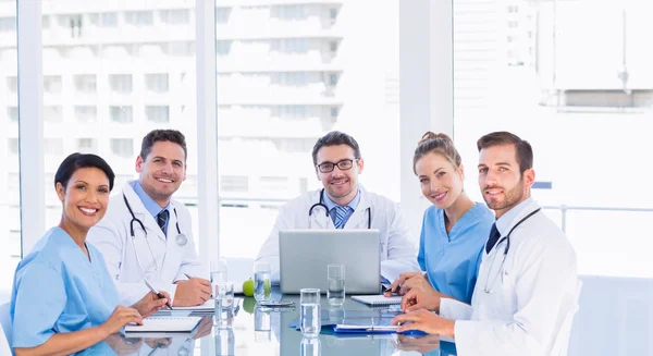 Equipo médico sonriente alrededor del escritorio en la oficina —  Fotos de Stock