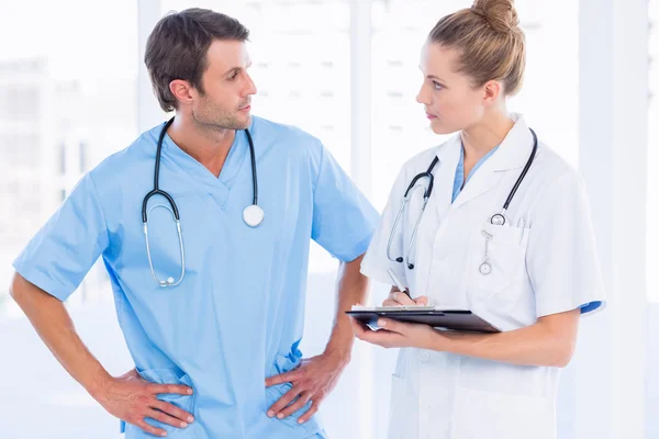 Male surgeon and female doctor with medical reports — Stock Photo, Image