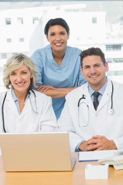 Médicos sonrientes con laptop en consultorio médico —  Fotos de Stock