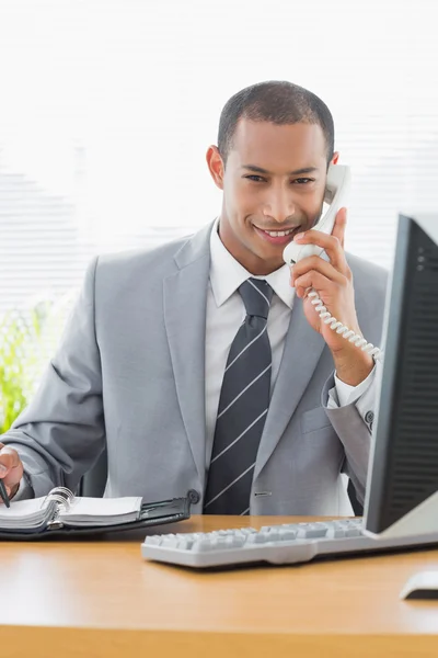 Lachende zakenman met behulp van computer en telefoon op kantoor — Stockfoto