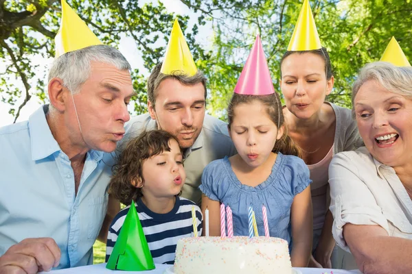 Extended family blowing cake outdoors — Stock Photo, Image