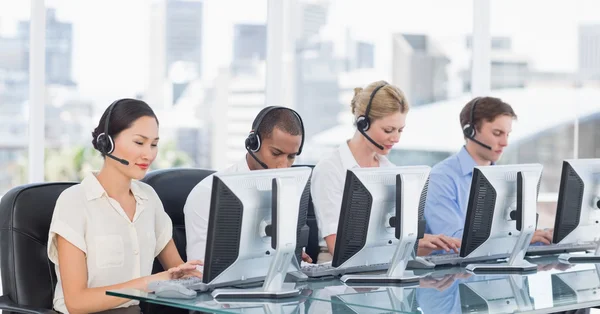 Kollegor med headset använder datorer på skrivbordet — Stockfoto