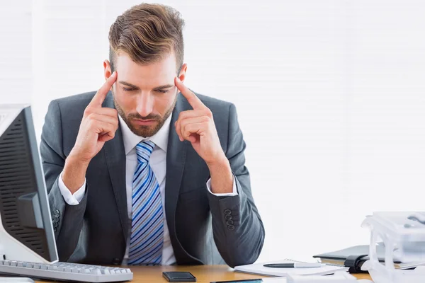 Zakenman met ernstige hoofdpijn aan bureau zitten — Stockfoto