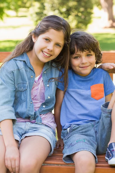 Jeune garçon et fille assis sur le banc du parc — Photo