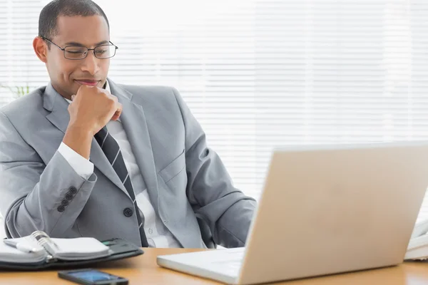 Улыбающийся бизнесмен смотрит на ноутбук в офисе — стоковое фото