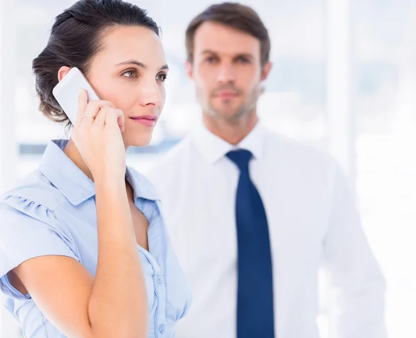 Woman on call with colleague in background at office — Stock Photo, Image