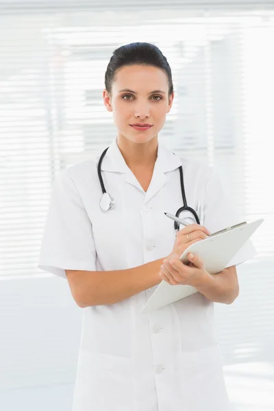 Beautiful young female doctor with clipboard — Stock Photo, Image