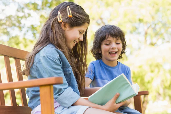 Side view of kids reading book on park bench — Stock Photo, Image