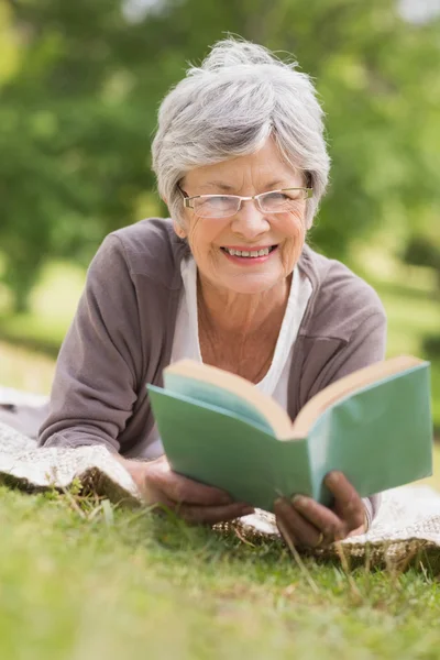 Seniorin liest im Park ein Buch — Stockfoto