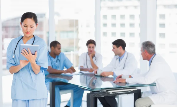 Surgeon using digital tablet with group around table in hospital — Stock Photo, Image