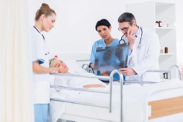 Médicos mostrando rayos X al paciente en la cama — Foto de Stock