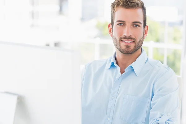 Sourire jeune homme en utilisant l'ordinateur dans le bureau — Photo