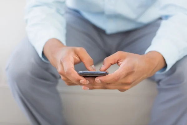 Mann schickt einen Text auf Couch sitzend — Stockfoto