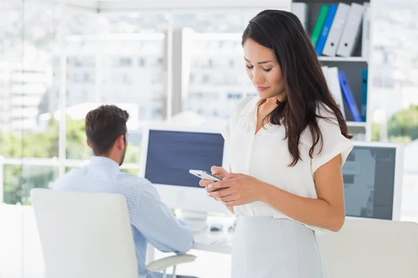 Messaggi di testo di artista femminile con collega in background — Foto Stock