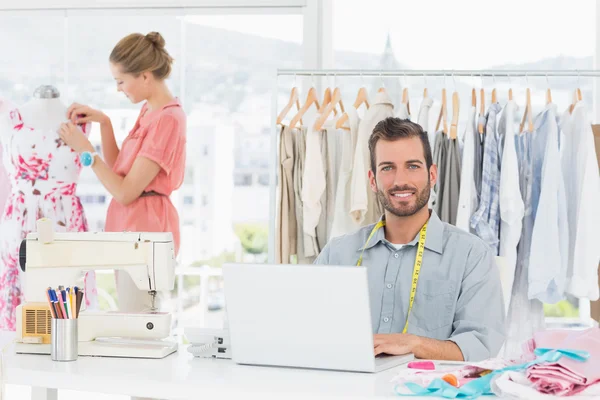 Homem usando laptop com designer de moda trabalhando no estúdio — Fotografia de Stock